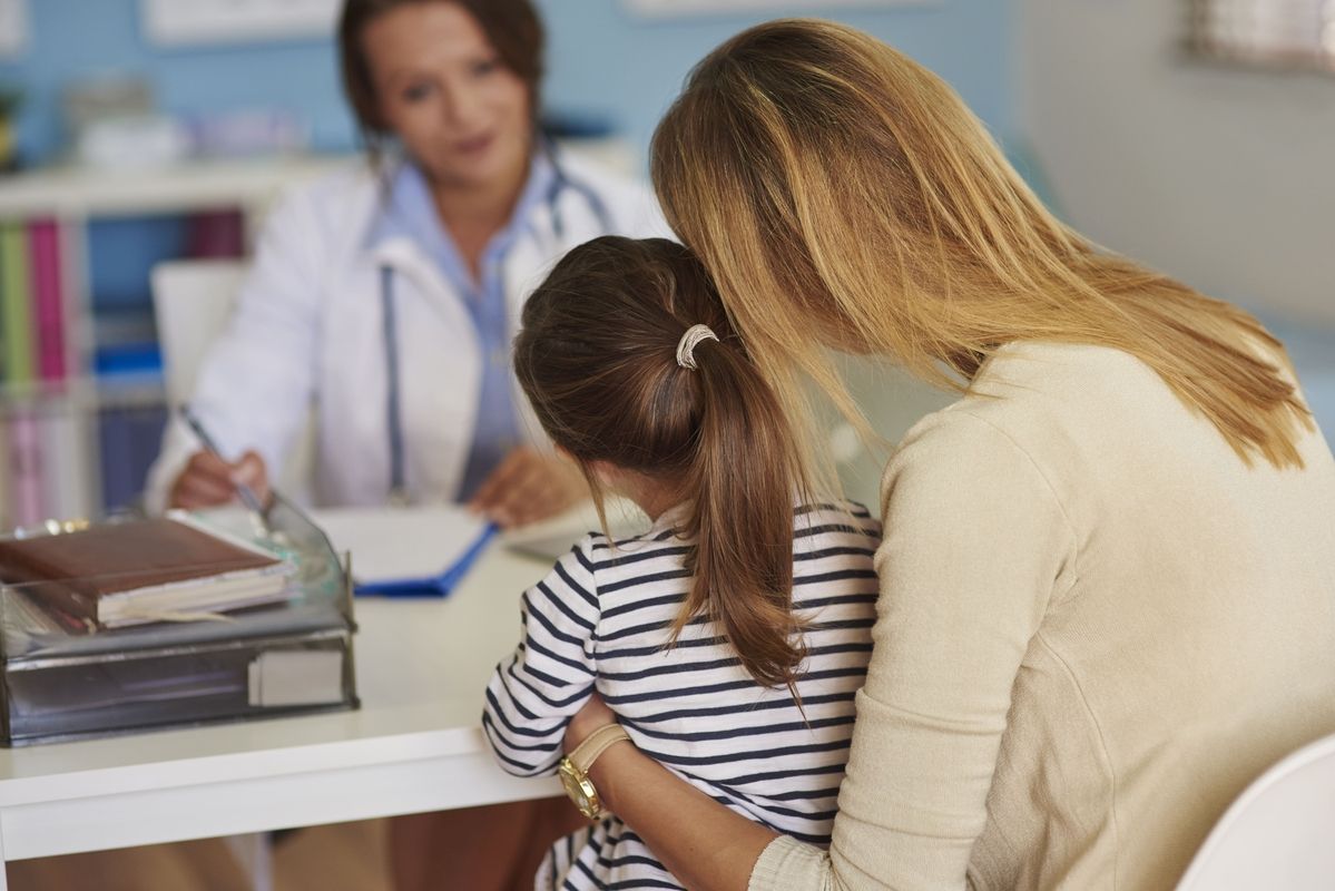 Mãe conforta filha durante consulta médica sobre medicamento incorporado ao SUS