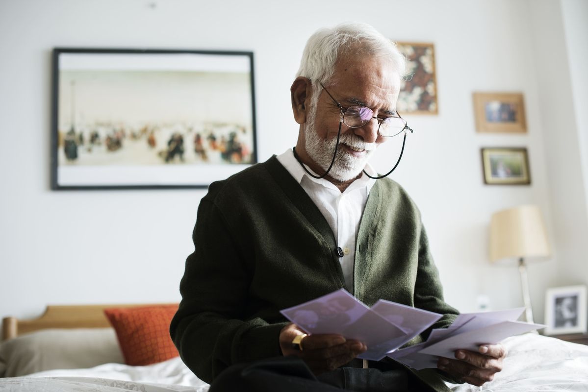 Pessoa idosa analisando documentos de reajuste do plano de saúde em casa